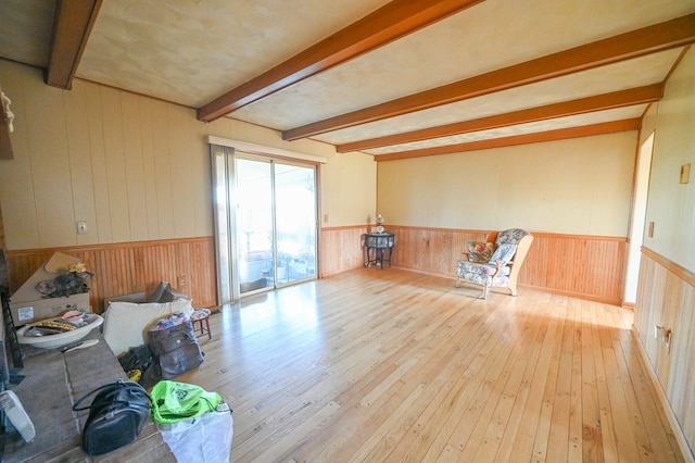 living room with wood walls, beamed ceiling, and light hardwood / wood-style flooring