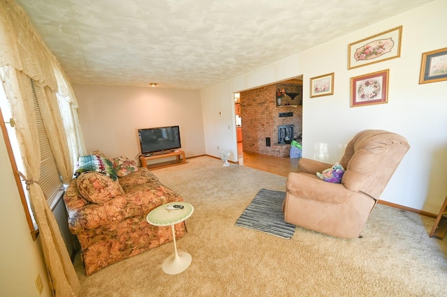 carpeted living room featuring a brick fireplace and a textured ceiling