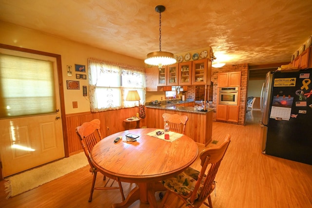 dining area with light hardwood / wood-style flooring and wood walls