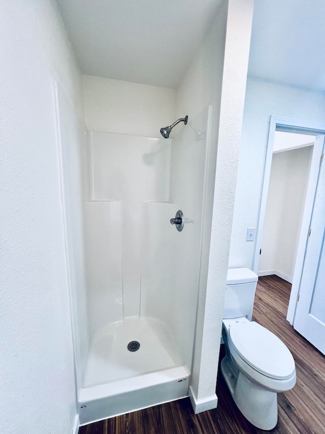 bathroom featuring toilet, a shower, and wood-type flooring