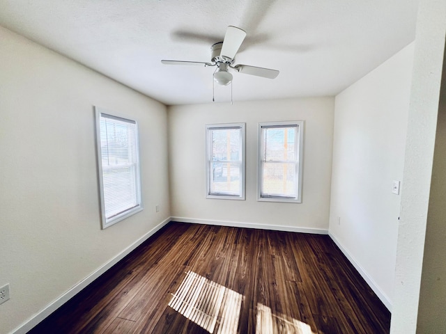 empty room with dark wood-type flooring, a wealth of natural light, and ceiling fan