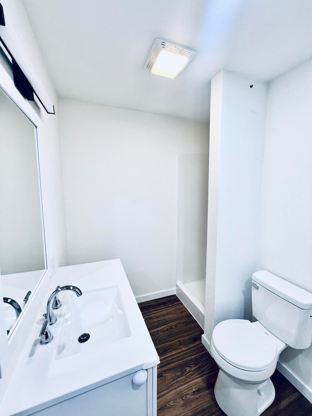 bathroom with a shower, wood-type flooring, vanity, and toilet