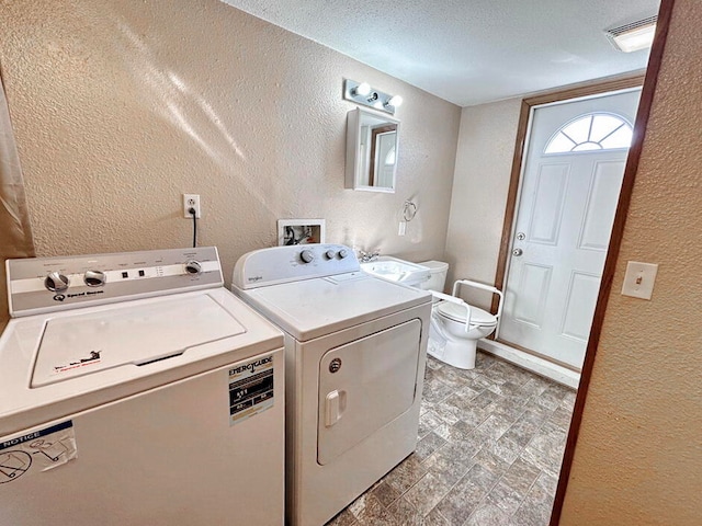 laundry room featuring washing machine and dryer and a textured ceiling