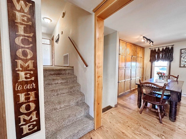 stairway featuring wood-type flooring and track lighting