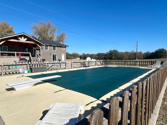 view of swimming pool featuring a diving board and a patio