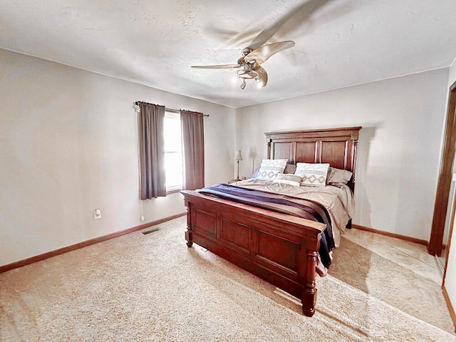 bedroom featuring a textured ceiling, light colored carpet, and ceiling fan