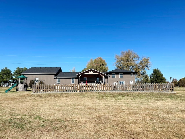 rear view of house with a playground and a yard