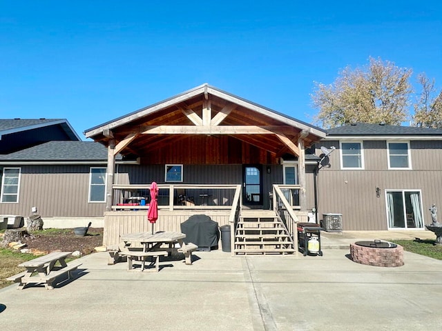 rear view of house featuring a fire pit, central AC, and a patio area