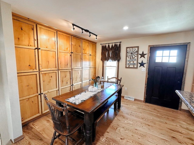 dining room featuring plenty of natural light, rail lighting, and light hardwood / wood-style floors