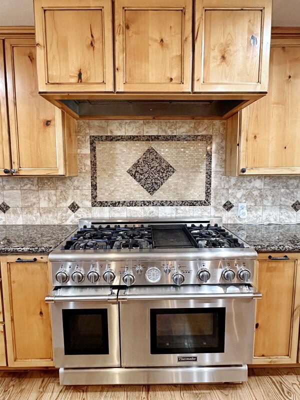 kitchen featuring dark stone counters, tasteful backsplash, and double oven range