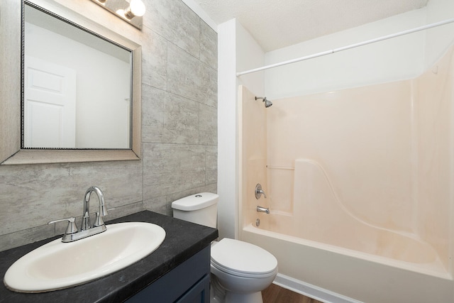 full bathroom with tile walls, vanity, a textured ceiling, shower / bathing tub combination, and toilet