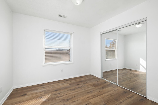 unfurnished bedroom featuring dark wood-type flooring and a closet