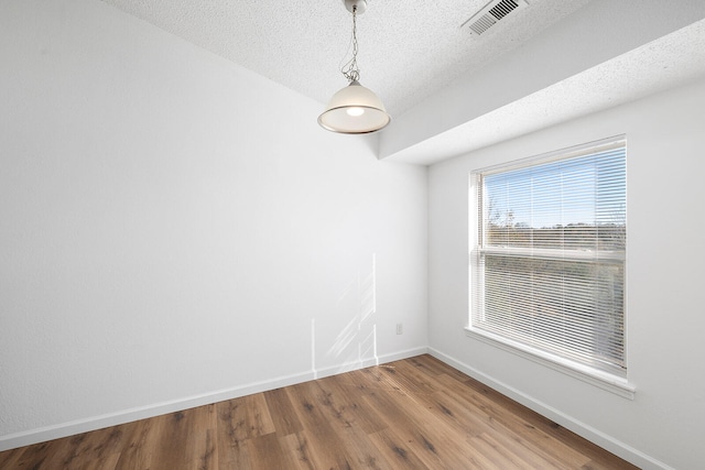 empty room featuring wood-type flooring and a textured ceiling