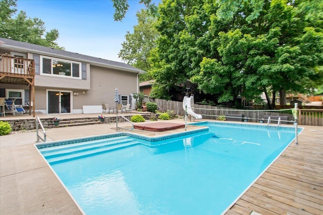 view of pool with a wooden deck, a patio, and a water slide