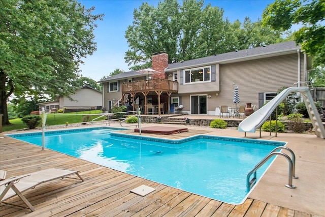 view of pool featuring a water slide, a patio area, and a wooden deck