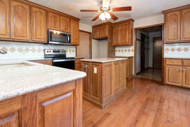 kitchen featuring light hardwood / wood-style floors, sink, tasteful backsplash, ceiling fan, and appliances with stainless steel finishes