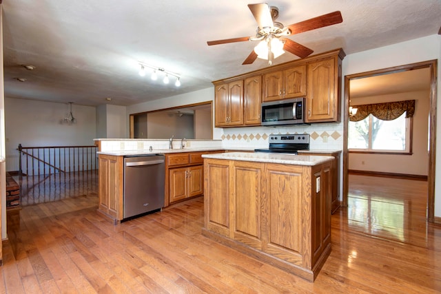 kitchen featuring stainless steel appliances, light hardwood / wood-style floors, a center island, sink, and tasteful backsplash