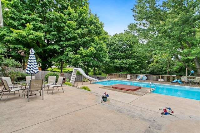 view of pool featuring a water slide and a patio