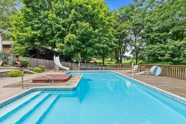 view of swimming pool with a water slide and a deck