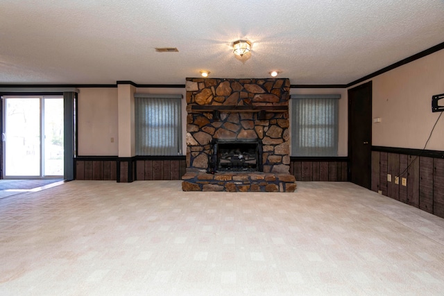 unfurnished living room with wood walls, ornamental molding, a textured ceiling, carpet, and a fireplace