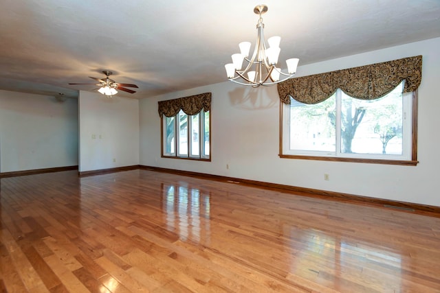 unfurnished room with hardwood / wood-style floors and ceiling fan with notable chandelier