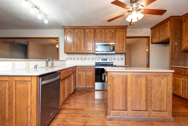 kitchen with stainless steel appliances, backsplash, a textured ceiling, sink, and light hardwood / wood-style flooring