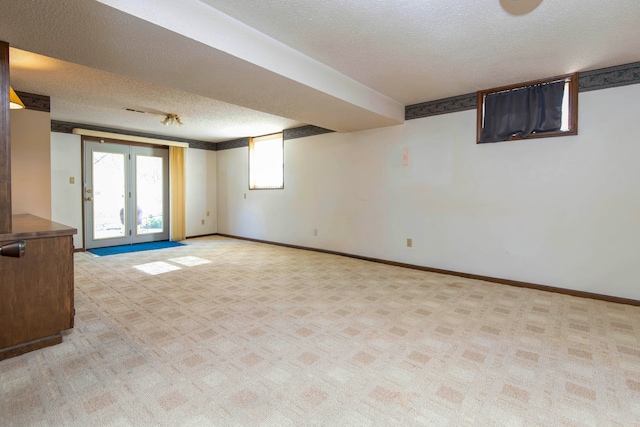 basement with a textured ceiling, light carpet, and french doors