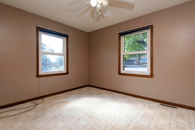 carpeted spare room with a textured ceiling, a healthy amount of sunlight, and ceiling fan