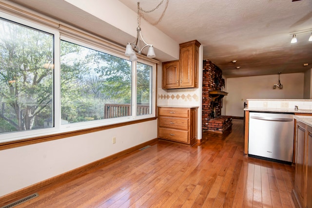 kitchen featuring light hardwood / wood-style floors, decorative backsplash, a chandelier, stainless steel dishwasher, and decorative light fixtures