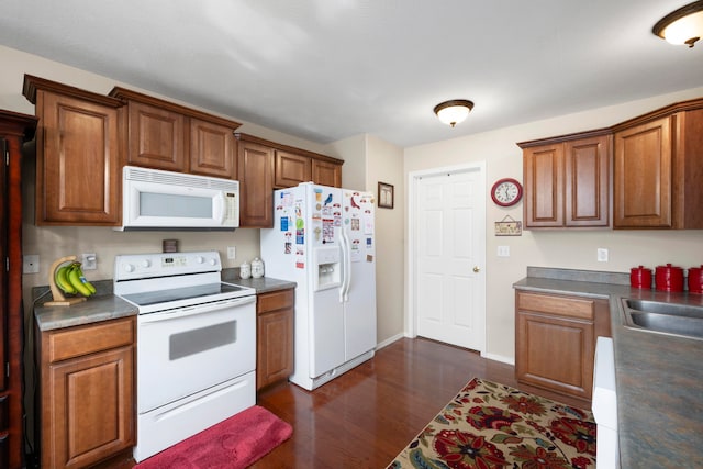 kitchen featuring dark hardwood / wood-style flooring, white appliances, and sink