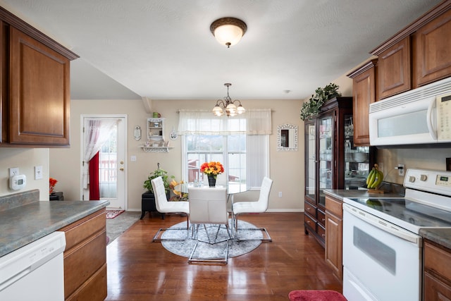 kitchen with plenty of natural light, a chandelier, white appliances, and dark hardwood / wood-style flooring