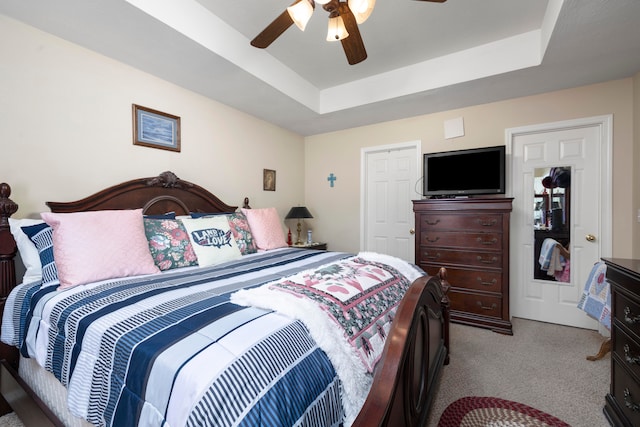 bedroom with light colored carpet, ceiling fan, and a raised ceiling