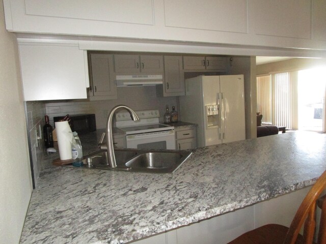 27038 Hickory Dr, Eagle Rock, MO 65641 - kitchen with under cabinet range hood, white appliances, decorative backsplash, a peninsula, and a sink