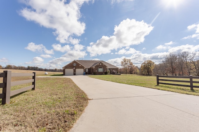 view of front of home featuring a garage, a rural view, and a front yard