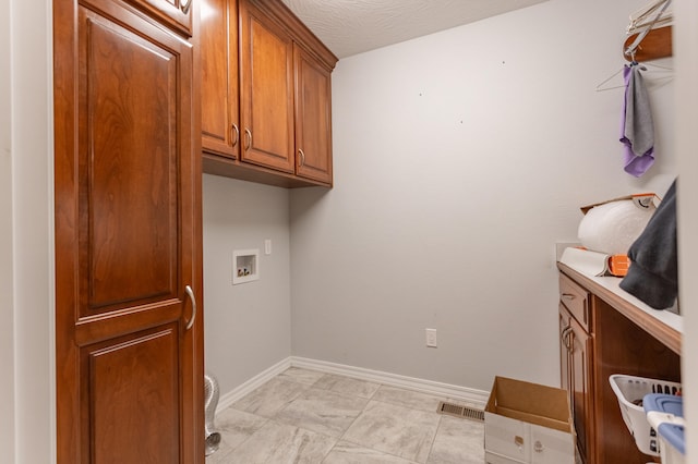 laundry room featuring washer hookup, cabinets, and a textured ceiling