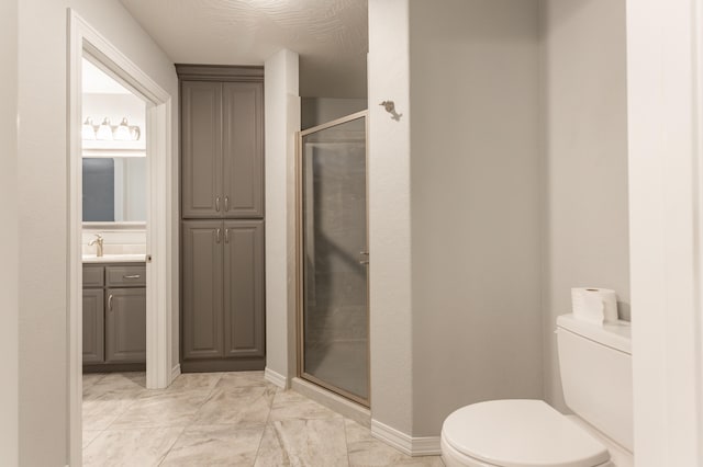 bathroom with vanity, a textured ceiling, toilet, and a shower with door