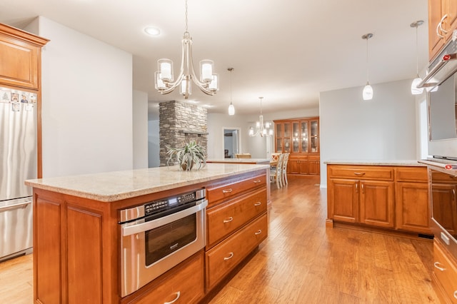 kitchen with hanging light fixtures, light wood-type flooring, appliances with stainless steel finishes, and a center island