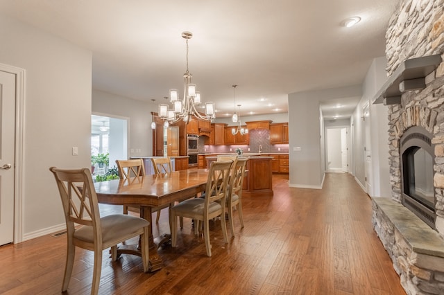 dining area featuring a fireplace, light hardwood / wood-style floors, and an inviting chandelier