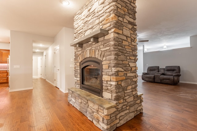 unfurnished living room featuring a fireplace, wood-type flooring, and ceiling fan