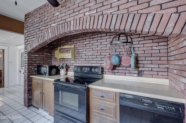 kitchen featuring light tile patterned floors, brick wall, and black appliances