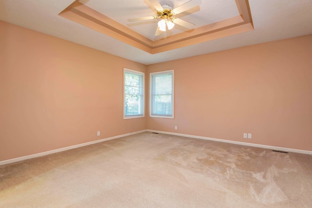 spare room with light colored carpet, ceiling fan, and a tray ceiling