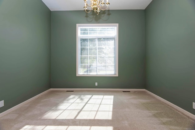 unfurnished room with light colored carpet and a notable chandelier