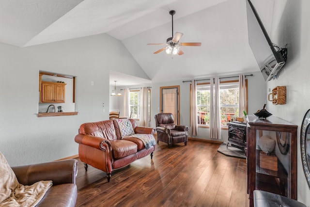 living room with a wood stove, dark hardwood / wood-style floors, high vaulted ceiling, sink, and ceiling fan