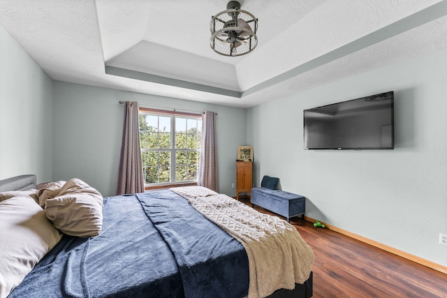 bedroom featuring hardwood / wood-style flooring, a textured ceiling, and a raised ceiling