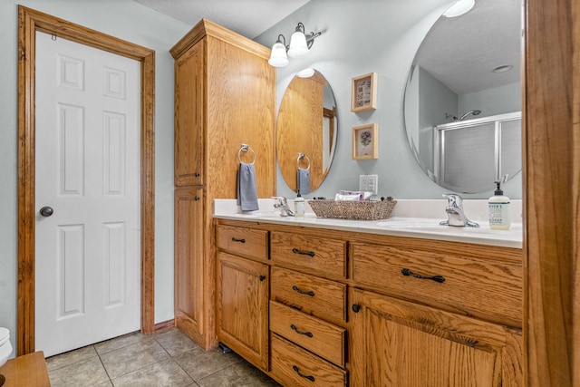 bathroom featuring vanity, a shower with shower door, and tile patterned flooring