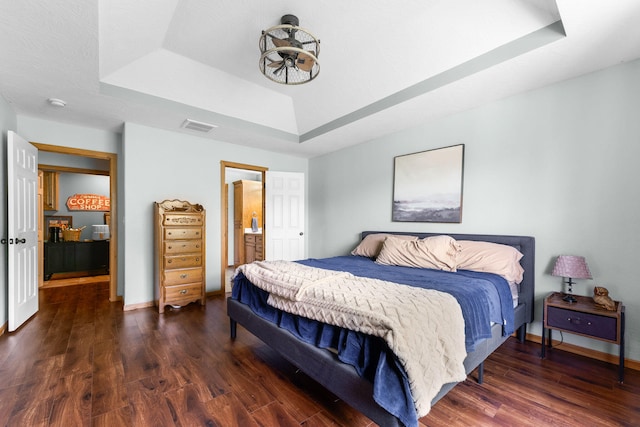 bedroom with dark hardwood / wood-style flooring and a tray ceiling