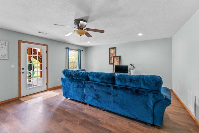 living room with a textured ceiling, wood-type flooring, and ceiling fan