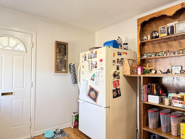 kitchen with white refrigerator, a textured ceiling, and hardwood / wood-style flooring