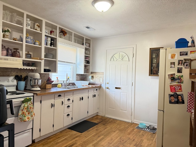 kitchen featuring white cabinetry, a textured ceiling, sink, light hardwood / wood-style floors, and white appliances