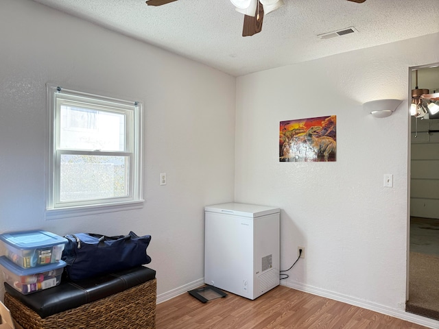 laundry room featuring a textured ceiling, ceiling fan, and light hardwood / wood-style flooring